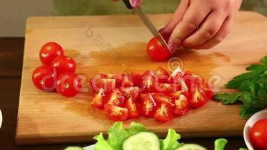 一个女人正在切樱桃西红柿做蔬菜沙拉。 特写